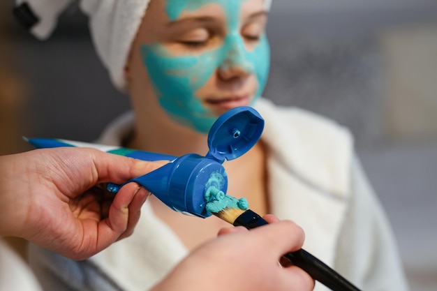 Máscara de peeling facial Menina adolescente aplicando máscara facial de argila Tratamentos de beleza