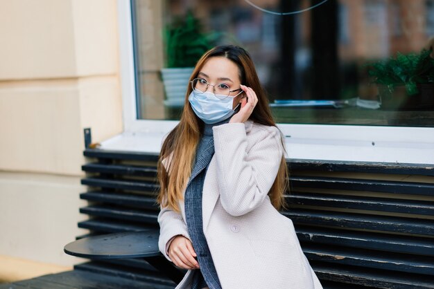Máscara de proteção contra a propagação do vírus da gripe contra doenças e vírus da gripe. mulher asiática usando máscara cirúrgica no rosto em espaços públicos. cuidados de saúde.