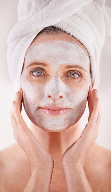 Máscara de spa ou mulher em retrato para cuidados com a pele facial em estúdio com desintoxicação natural ou cosméticos com toalha Confidância de modelo ou rosto com loção para tratamento anti-envelhecimento ou beleza em fundo branco