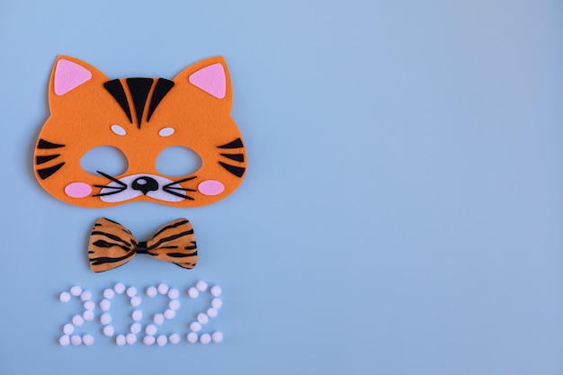 Máscara de tigre de carnaval laranja brilhante borboleta tigre no pescoço em um fundo azul Símbolo de 2022