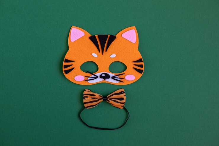 Foto máscara de tigre de carnaval laranja brilhante e borboleta tigre no pescoço em um fundo verde