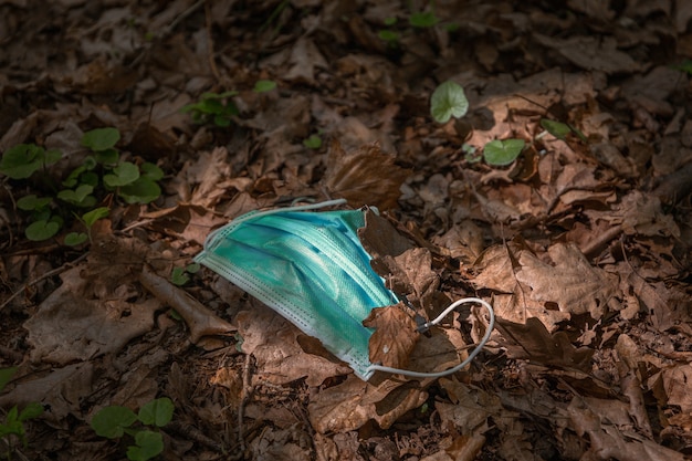 Foto máscara facial contra covid19 deixada no chão no meio de uma floresta