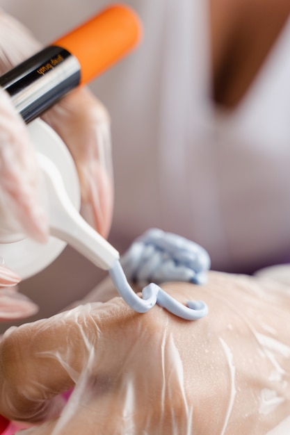 Máscara facial de gel azul na escova. Preparação para procedimento de peeling cosmético.