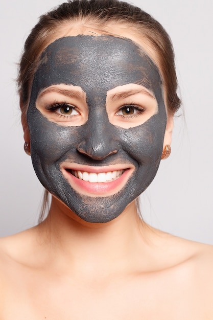 Foto máscara facial de mulher. retrato de menina bonita, removendo a máscara preta cosmética da pele do rosto. closeup de mulher jovem e atraente com maquiagem natural e máscara de peeling cosmético no rosto. alta resolução