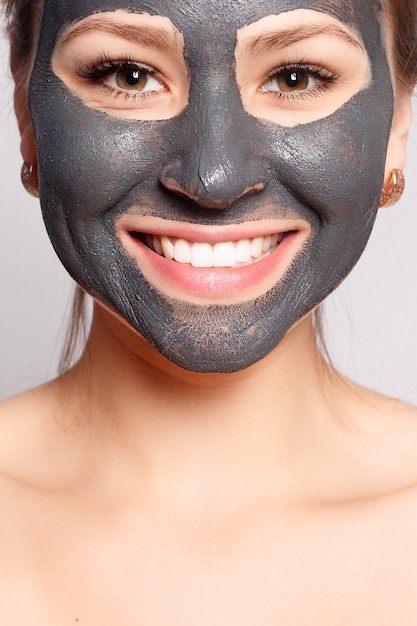 Foto máscara facial de mulher. retrato de menina bonita, removendo a máscara preta cosmética da pele do rosto.