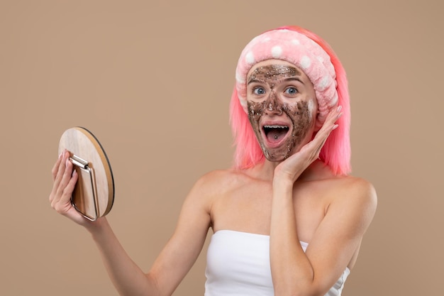 Máscara facial. Menina de cabelo rosa com máscara hidratante de chocolate no rosto