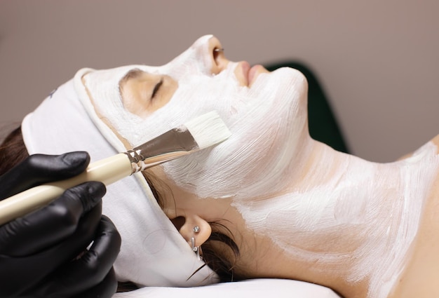 Máscara facial tratamento de beleza de spa Mulher aplicando máscara facial de argila no salão de spa cuidados com a pele