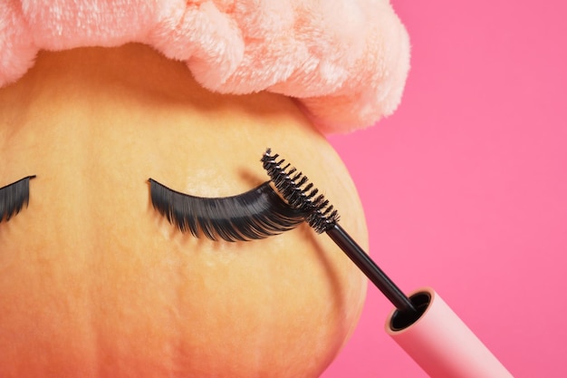 Mascara in Mock-up leere rosa Verpackung und Kürbis mit falschen Wimpern auf rosa Hintergrund kopieren