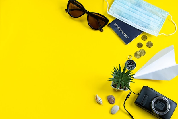 Máscara médica de pasaporte y gafas de sol sobre un fondo amarillo Concepto de viaje seguro