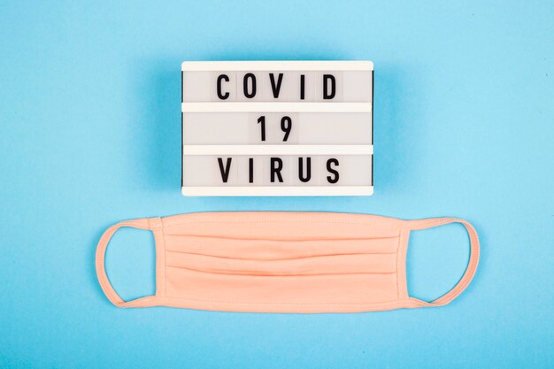 Una máscara médica rosa con la inscripción del virus Covid 19.