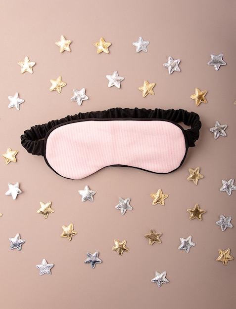 Foto máscara para dormir no fundo pastel estrelas douradas e prateadas ao redorconceito de ritmos circadianos