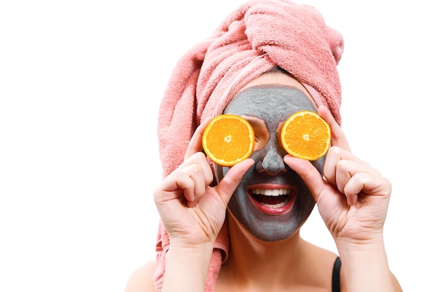 Máscara para pele de mulher, garota feliz e divertida faz máscara para pele de rosto, garota fecha os olhos com laranja, garota está sorrindo, foto isolada