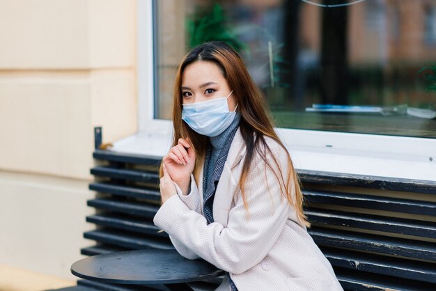 Máscara de protección contra la propagación del virus de la gripe que protege contra los virus y enfermedades de la gripe. Mujer asiática con mascarilla quirúrgica en la cara en espacios públicos. Cuidado de la salud.