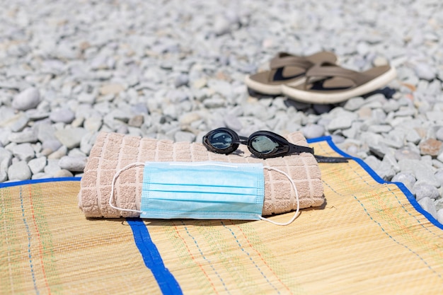 Foto máscara protectora, toalla de playa, gafas de natación en la playa.