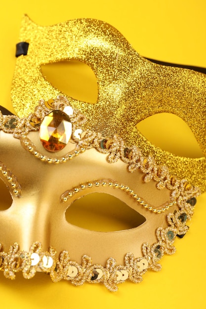 Máscaras de carnaval douradas em close de fundo amarelo