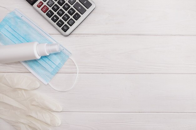 Máscaras médicas, aerosol antiséptico, guantes quirúrgicos y calculadora en un blanco