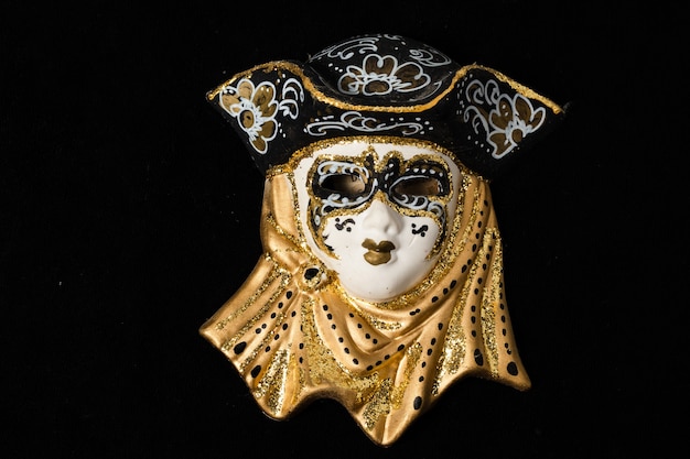 Máscaras venecianas de adorno de cerámica blanca y negra con reflejos dorados o dorados. Fondo negro.