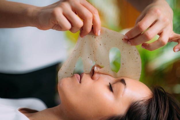 Mascarilla de belleza en el rostro de la mujer en el salón