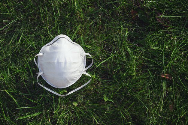 Mascarilla de coronavirus sobre hierba verde, concepto de salud, espacio de copia.