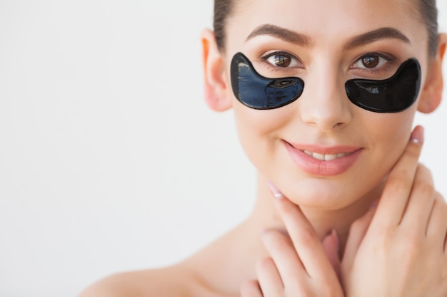 Mascarilla para el cuidado de la piel. Mujer con parches negros