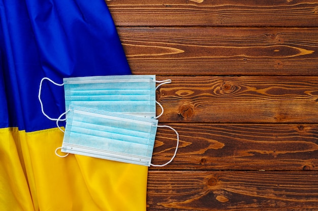 Mascarilla médica en la bandera de Ucrania sobre tabla de madera