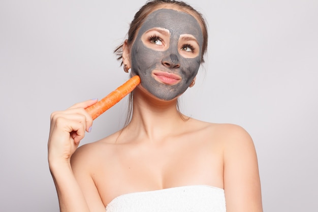 Mascarilla de mujer. Retrato de hermosa niña quitando la máscara de peeling cosmético negro de la piel facial. Primer plano de una mujer joven atractiva con maquillaje natural y mascarilla cosmética en la cara. Alta resolución