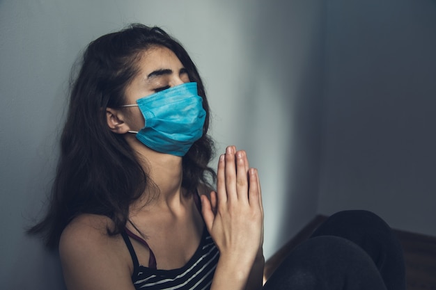 Mascarilla de mujer rezando en la habitación