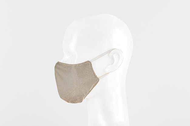 Mascarilla de tela beige sobre una cabeza simulada