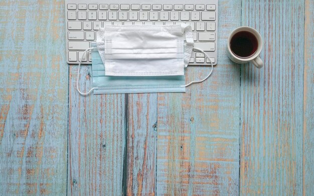 Mascarillas encima del teclado y café en la mesa de madera