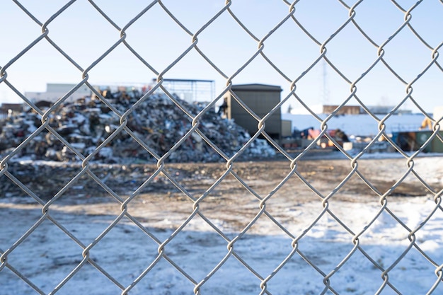 Maschendrahtzaun mit Müllrecyclingdeponie dahinter