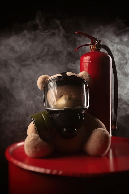 La mascota de los bomberos es un oso de peluche con una máscara de gas con un extintor de incendios en humo sobre un fondo oscuro