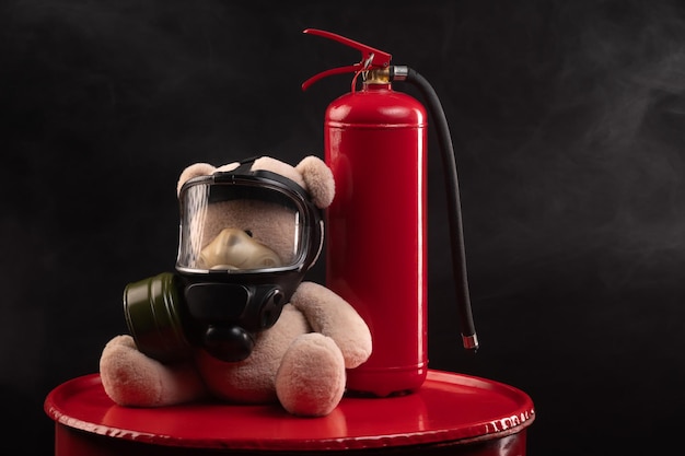 La mascota de los bomberos es un oso de peluche con una máscara de gas con un extintor de incendios en humo sobre un fondo oscuro