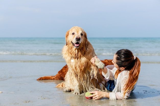 Mascotas amigables La mujer y la familia golden retriever pasando relajación en la playa tropical