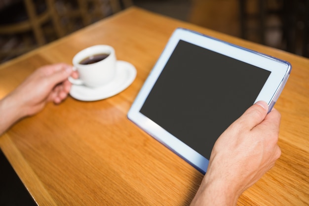 Masculinas mãos segurando tablet e café