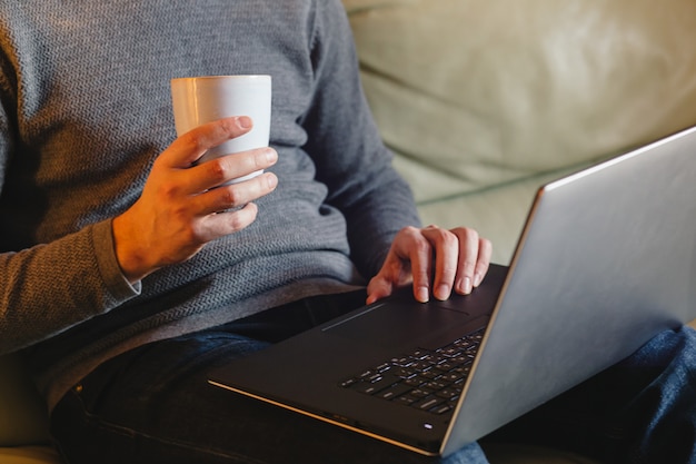 Masculinas mãos usando o laptop em casa