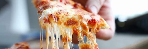 Masculino braço tomando fatia de queijo saborosa pizza fresca