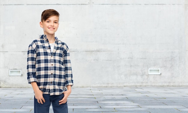 masculino, gênero, infância, moda e conceito de pessoas - menino sorridente em jeans e camisa quadriculada sobre fundo de rua urbana