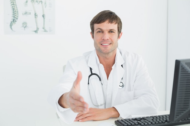 Masculino médico oferecendo um aperto de mão na mesa de escritório médica
