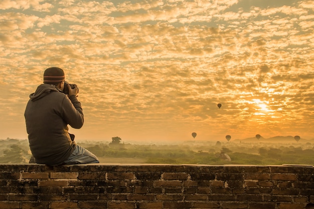 Foto masculino viajante fotografando templos em bagan myanmar ao nascer do sol
