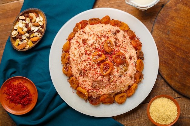 Masfouf de cuscús con frutos secos y nueces sobre una mesa de madera junto a sémola de azafrán y cuscús