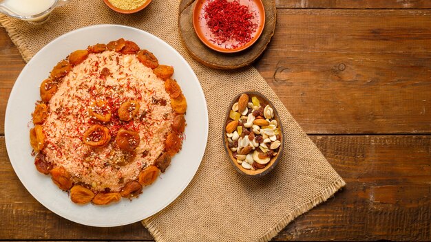 Masfouf de cuscús con leche de almendras en un plato sobre una mesa de madera junto a nueces de azafrán y cuscús