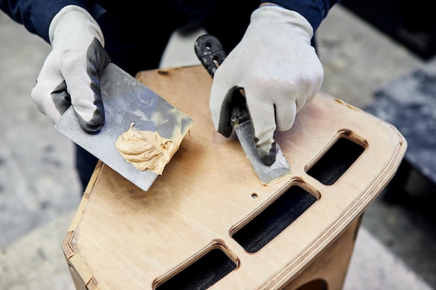 Masilla de madera Trabajador manual spackling productos de madera en la fabricación de carpintería Primer plano del proceso de trabajo