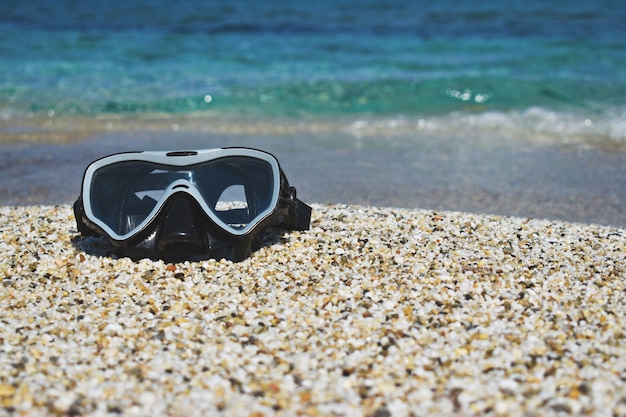 Maske zum Tauchen im Sand gegen das Meer