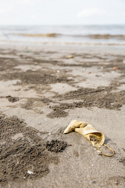 Masken werden am Strand im Meeresmüll entsorgt