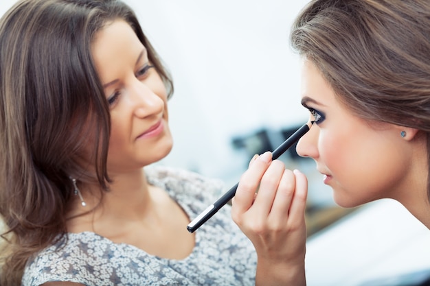 Maskenbildner, der Eyeliner auf das Unterlid des Modells aufträgt