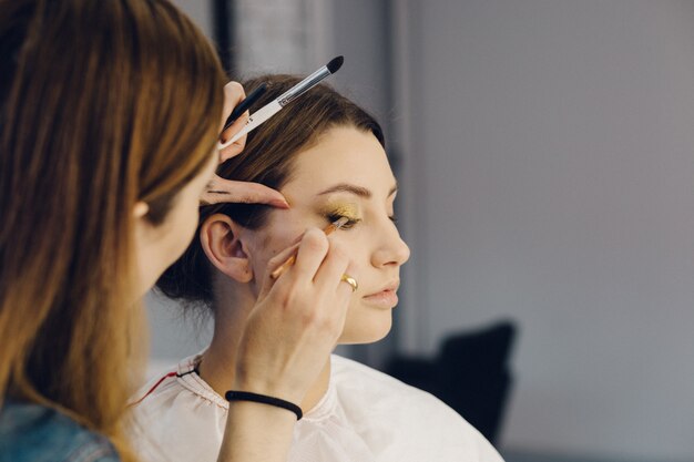 Foto maskenbildner, der lidschatten auf die augen des modells aufträgt