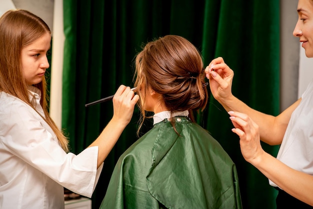 Maskenbildner und Friseur bereiten die Braut vor, die Frisur und Make-up in einem Schönheitssalon macht