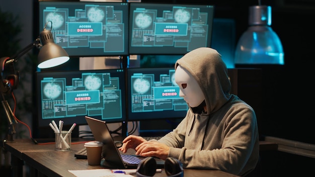 Maskierter Hacking-Dieb, der Informationen vom Datenbankserver stiehlt, Computerhardwaresystem hackt. Hacker mit Kapuze und Maske, der Viren-Malware erstellt und IT-Sicherheitsverletzungen im Büro durchführt.