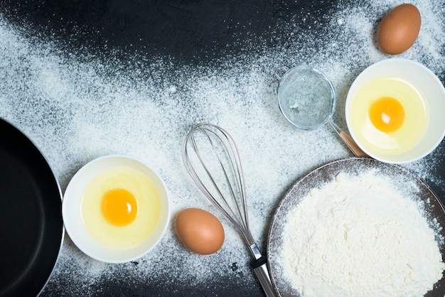 Maslenitsa ist ein traditioneller Feiertag im Februar. Zutaten zum Backen von Pfannkuchen-Eiern, Mehl, Schneebesen, Öl, Pfanne im Dunkeln