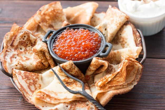 Foto maslenitsa panquecas de férias com caviar vermelho e creme azedo na mesa a tradição russa